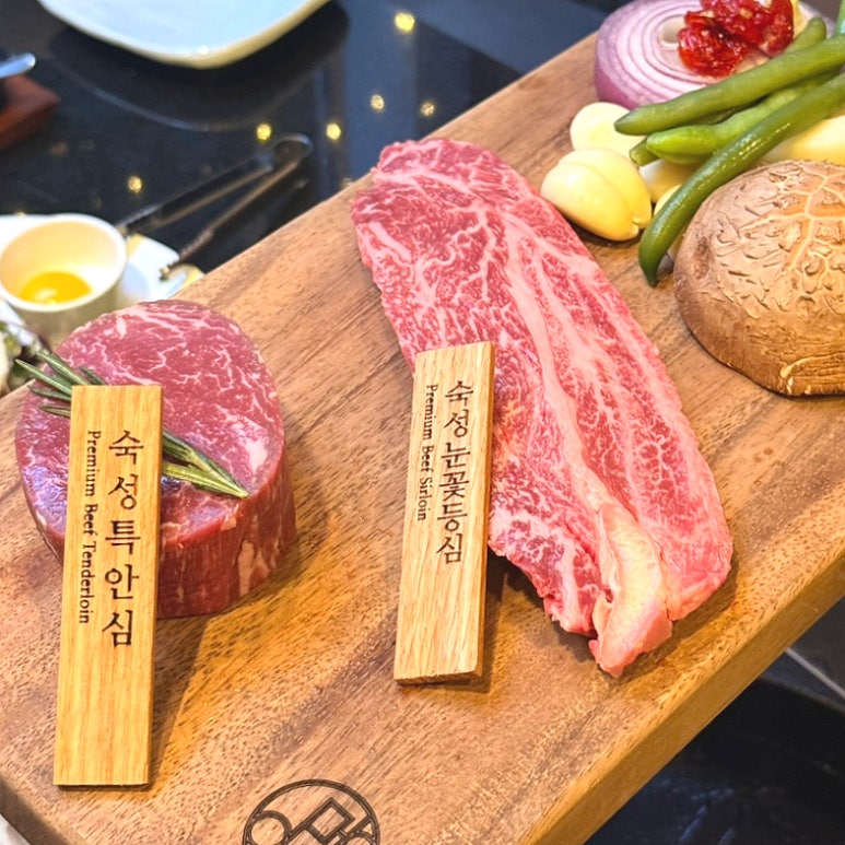 Premium dry-aged tenderloin and snowflake sirloin on a wooden board with engraved Korean wood markers